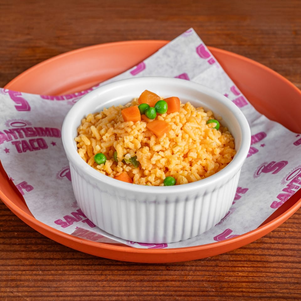 Orange-seasoned rice with peas and carrots served in a white bowl on a branded tray.
